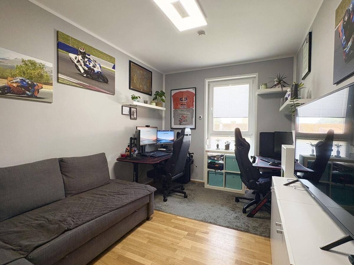 Funktionales Arbeitszimmer mit zwei Schreibtischen, Sofa und sportlicher Dekoration.