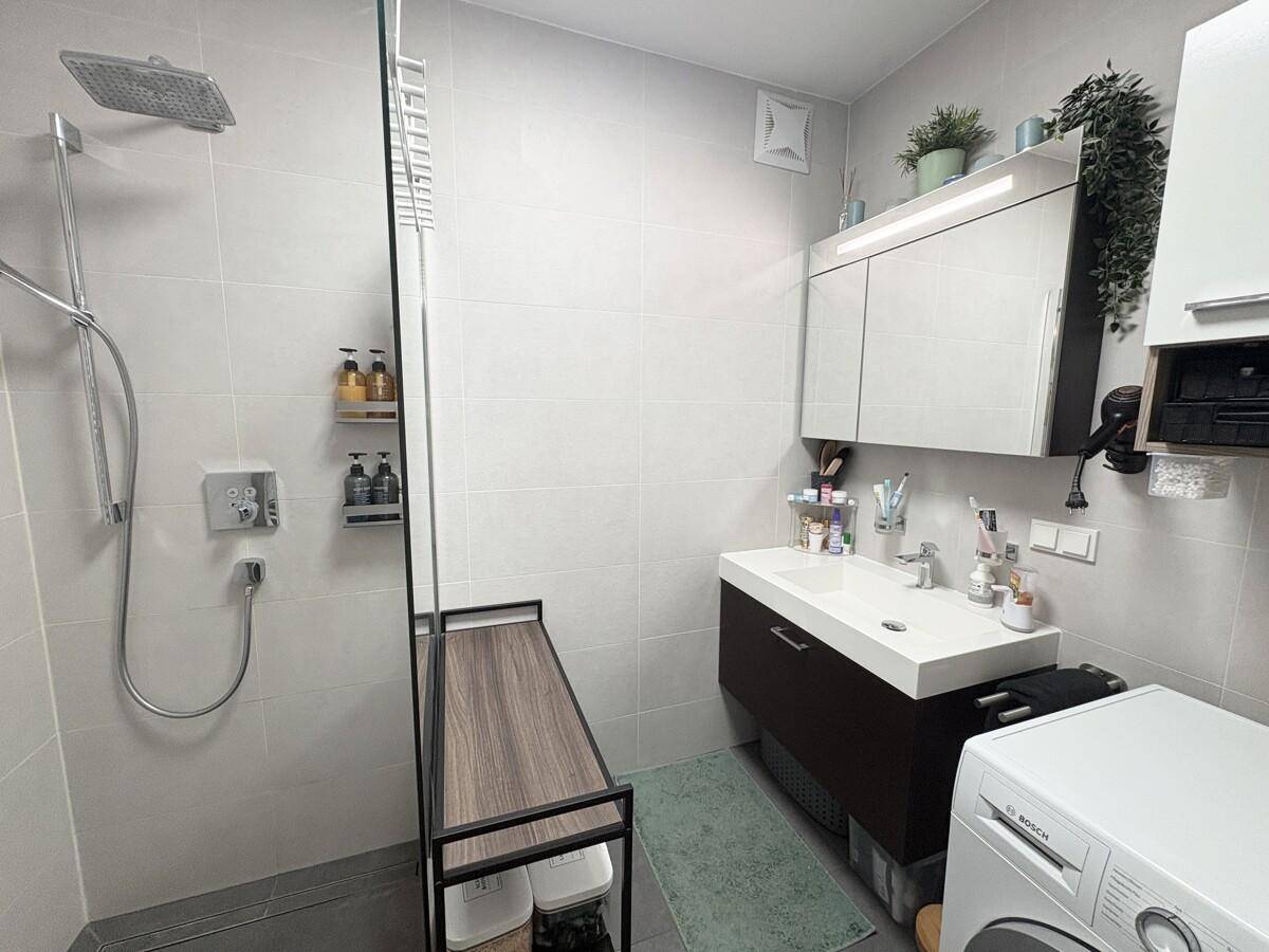 Modernes Badezimmer mit ebenerdiger Dusche, Einzelwaschbecken und Waschmaschine.
