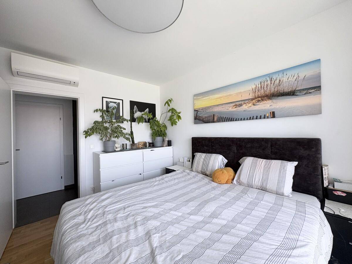 Helles Schlafzimmer mit Doppelbett, weißer Kommode und Klimaanlage.