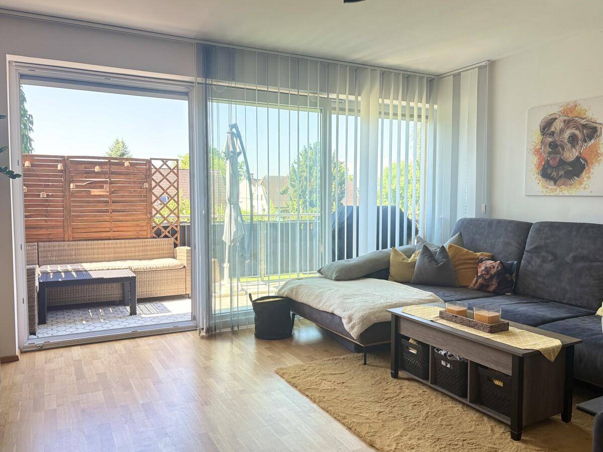 Gemütliches Wohnzimmer mit Sofa und großem Fensterbereich mit Zugang zum Balkon.
