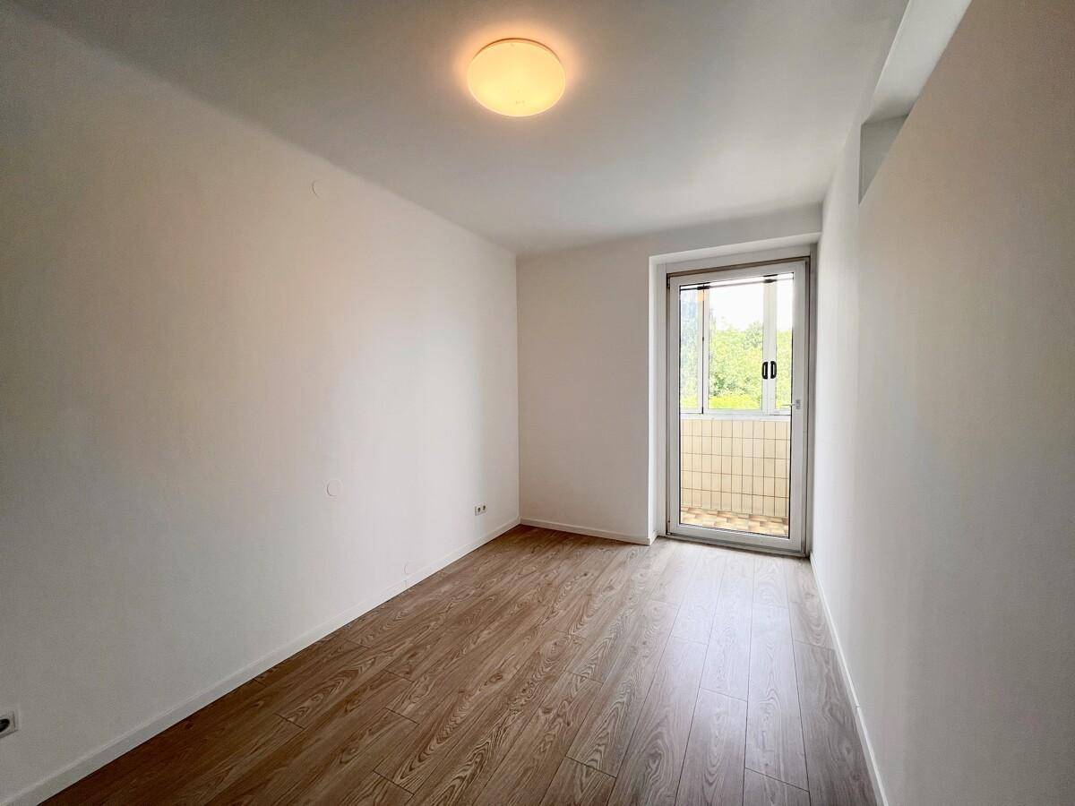 Helles Zimmer mit Laminatboden und Zugang zu einem Balkon, ideal als Schlafzimmer.