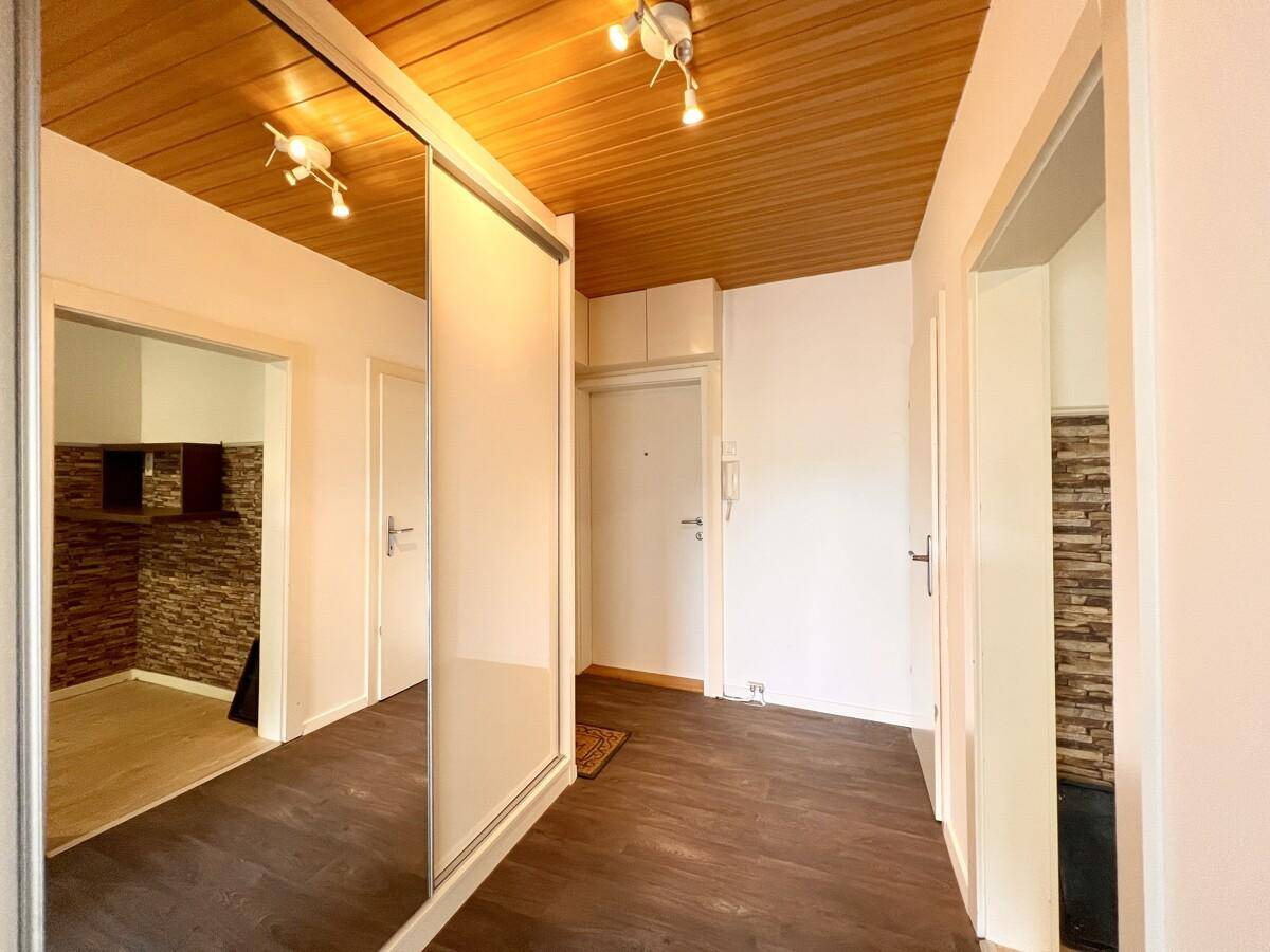 Eingangsbereich mit Holzpaneeldecke, Spiegelschränken und Zugang zur Küche und weiteren Zimmern.