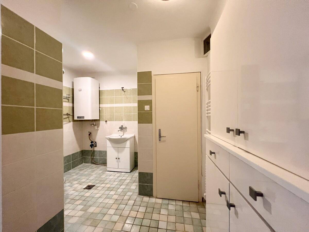 Badezimmer mit Fliesen in Grün- und Beigetönen, Waschbecken und Stauraum.