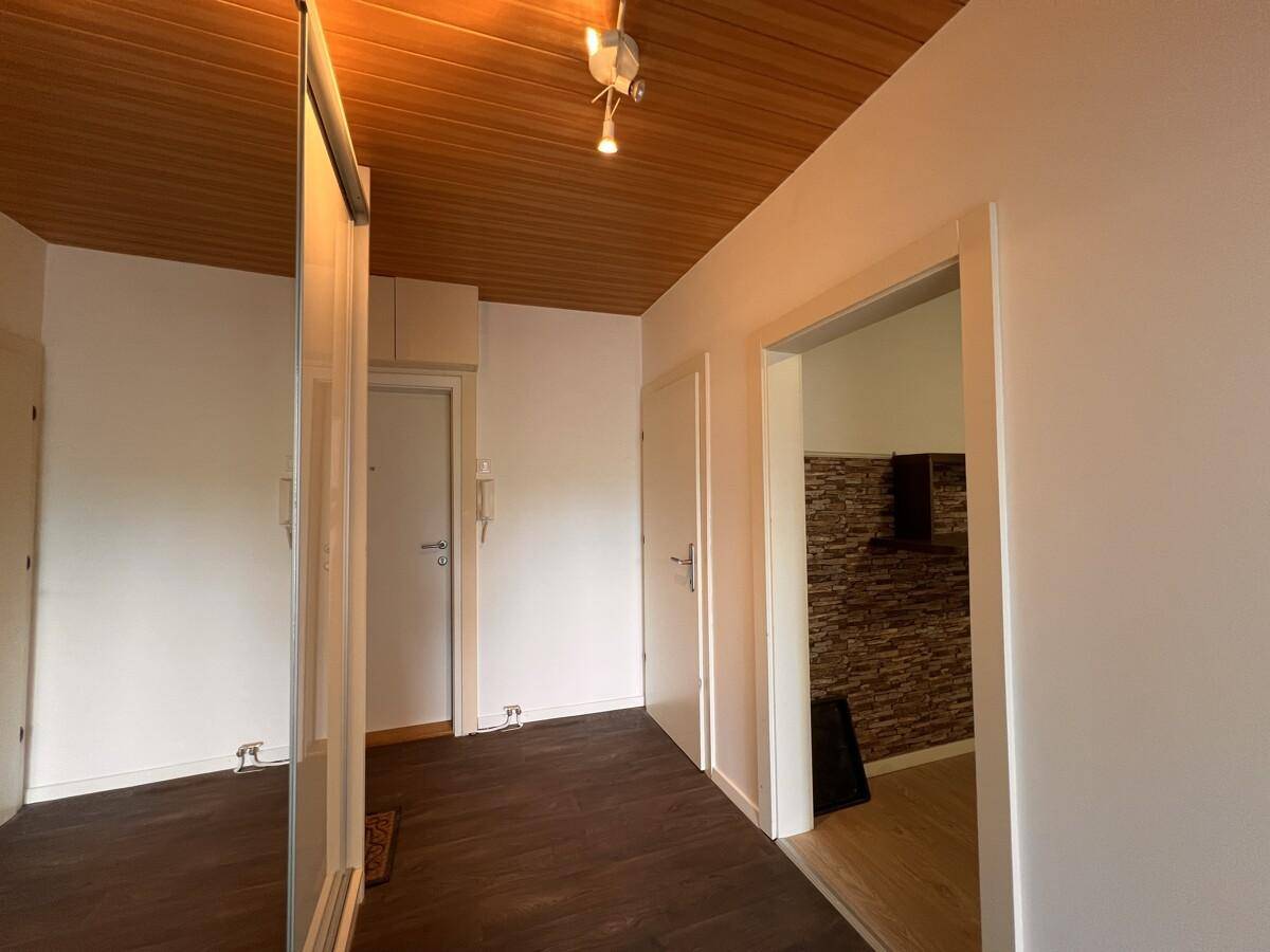 Flur mit Holzpaneeldecke, dunklem Laminatboden und Spiegelschränken, bietet Zugang zu den Räumen.