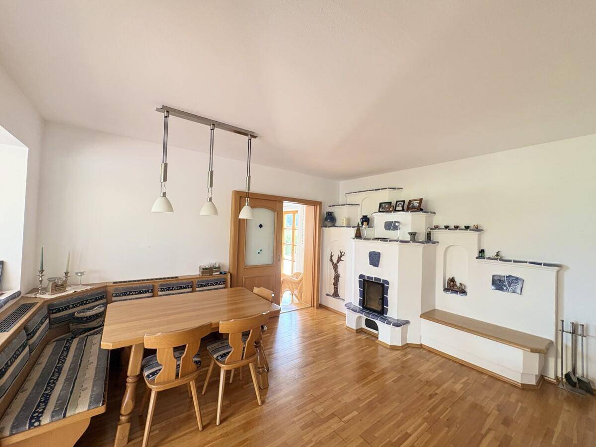 Gemütlicher Essbereich mit traditionellem Kachelofen und Holzboden, ideal für Familienessen.