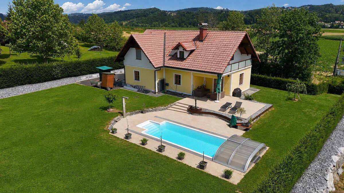 Weitläufiger Garten mit Pool und Liegefläche, eingebettet in eine idyllische Naturlandschaft.