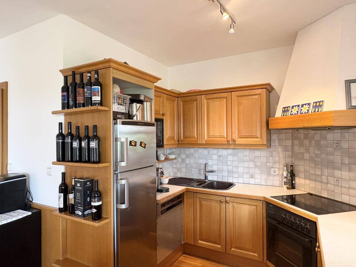 Gut ausgestattete Holzküche mit Kühlschrank, Spülmaschine und Kochfeld.