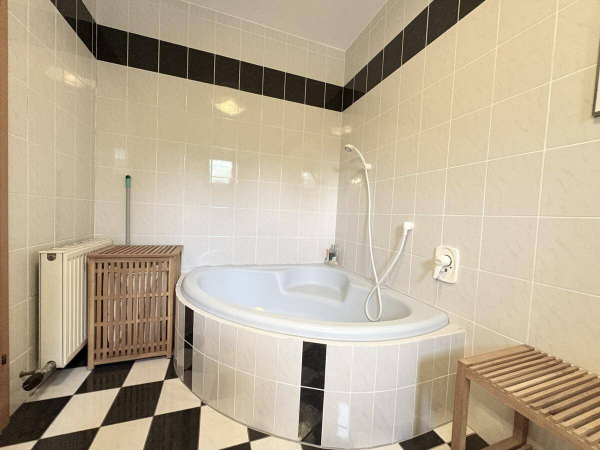 Badezimmer mit Eckbadewanne und schwarz-weiß gefliestem Boden, im Stil der 80er Jahre.