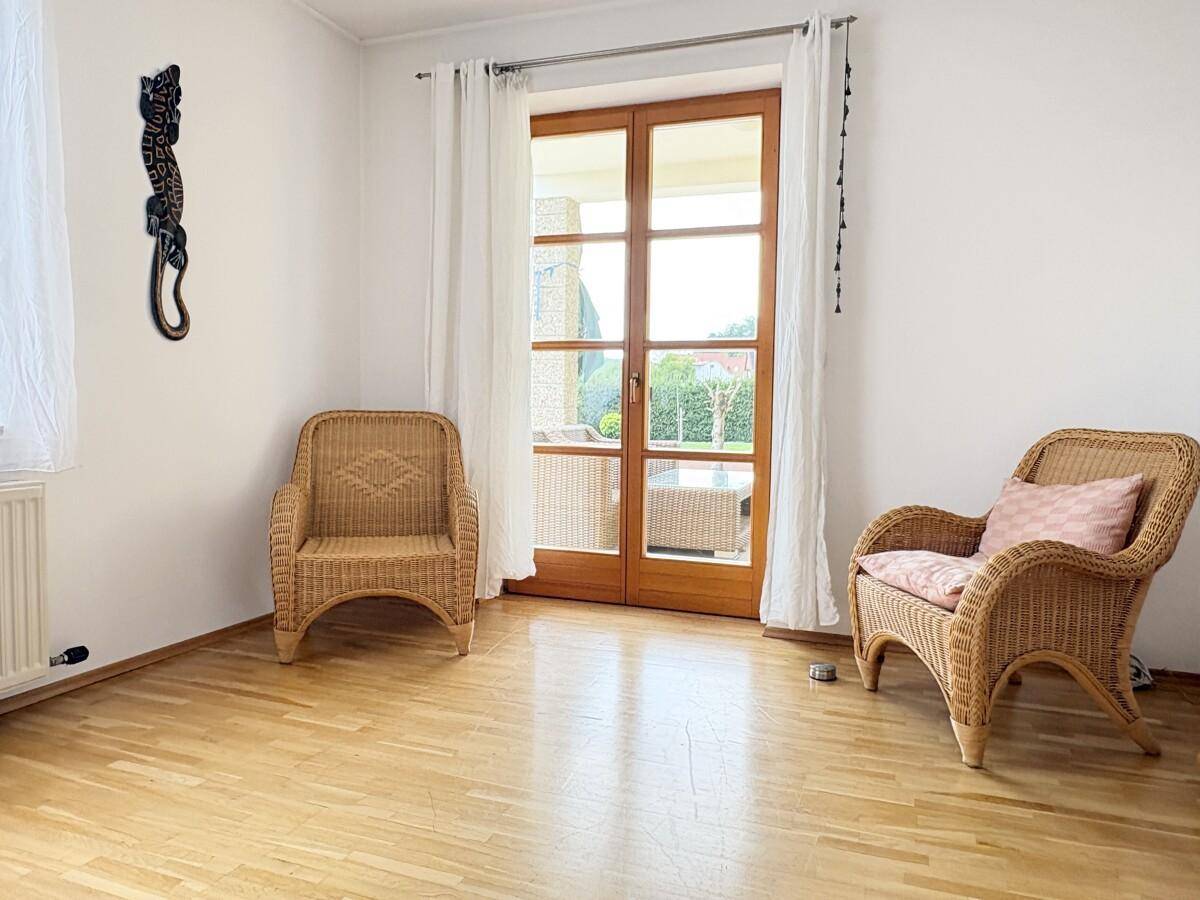 Heller Raum mit Korbsesseln und Zugang zu einem Außenbereich, ideal zum Entspannen.