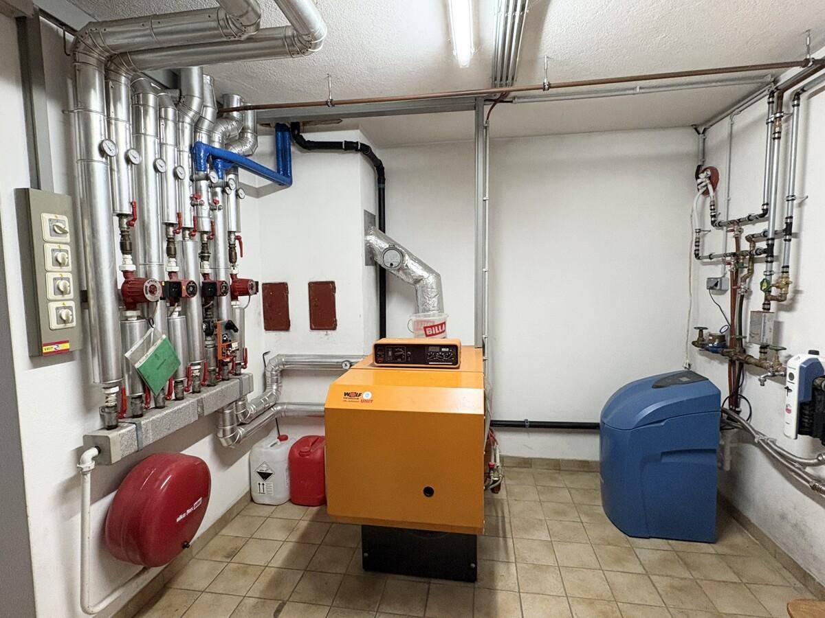 Heizungsraum im Keller mit moderner Heizungsanlage und vielen Rohren.