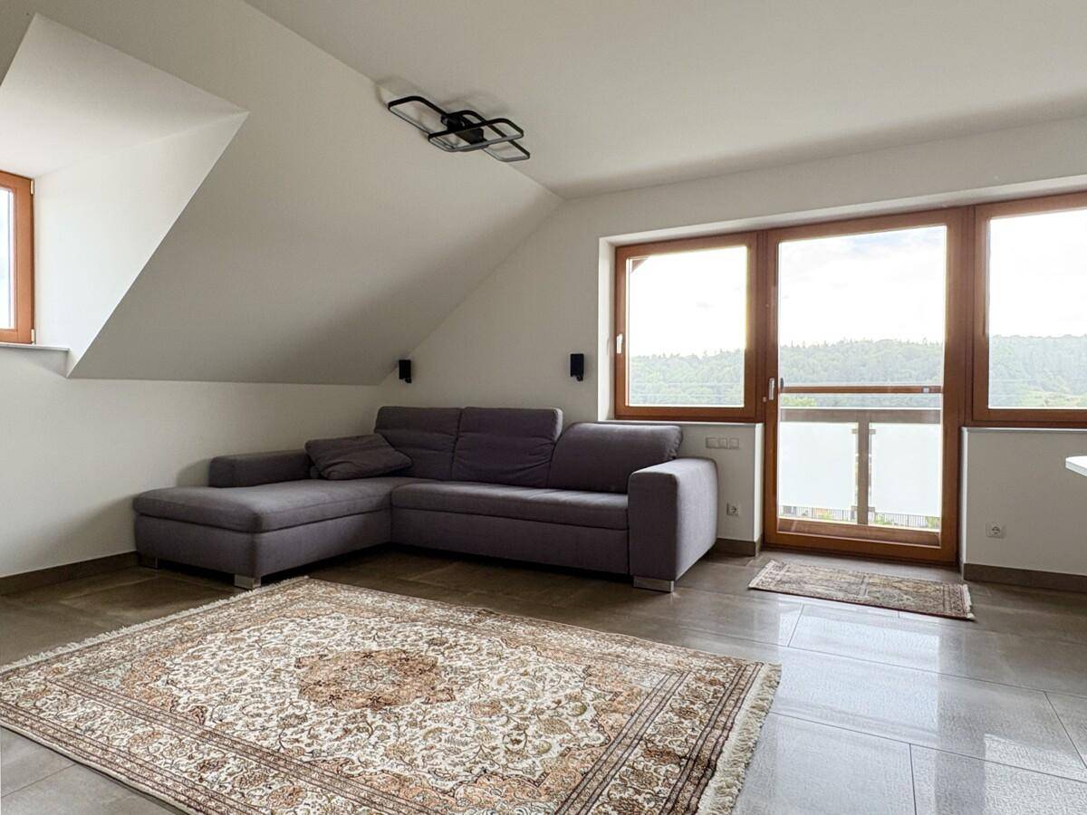 Helles Wohnzimmer im Dachgeschoss mit Zugang zu einem französischen Balkon und weitem Blick.