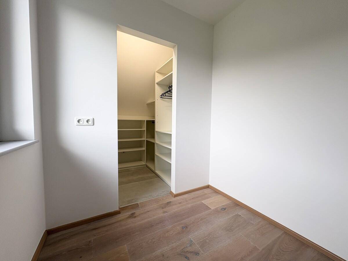 Kleiner Raum mit integriertem begehbarem Kleiderschrank und Holzfußboden.