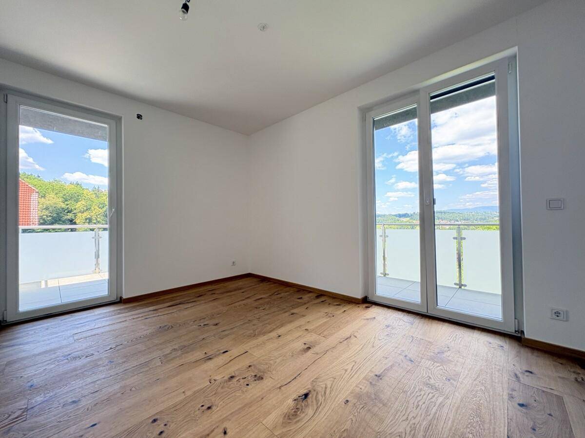 Helles Schlafzimmer mit Holzboden und Zugang zu einem Balkon mit Weitblick.