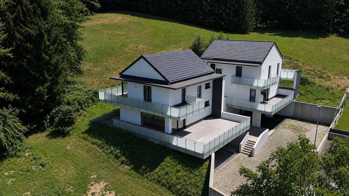 Neubau-Doppelhaushälften mit großzügigen Terrassen und Balkonen, umgeben von Natur.
