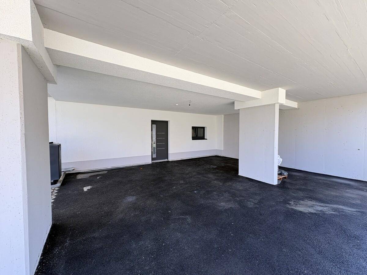Überdachter Parkbereich oder Garage im Untergeschoss mit Zugang zum Haus.