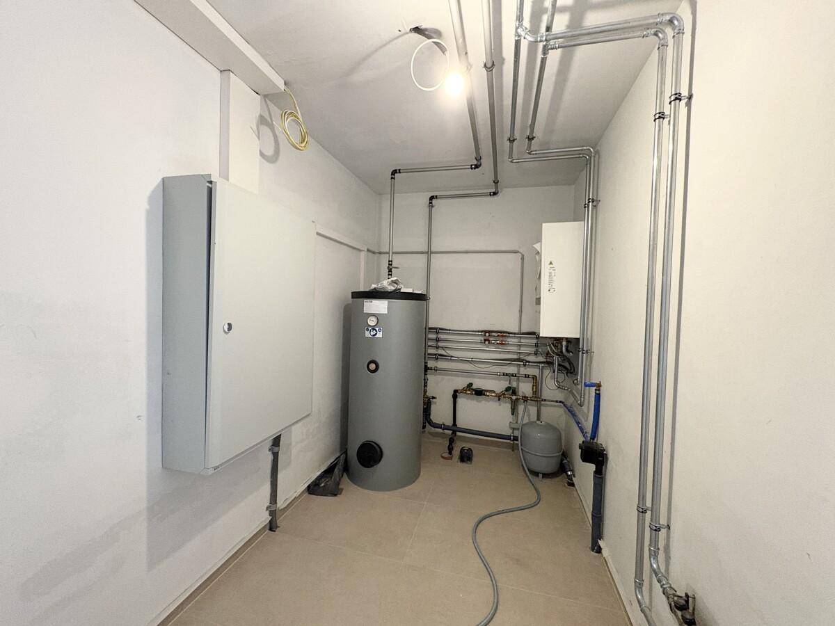 Technikraum mit Heizungsanlage, Warmwasserspeicher und sichtbaren Installationen.