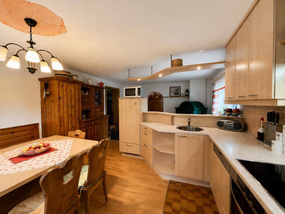 Funktionale Küche mit hellen Holzschränken, Essbereich und Blick in den Wohnbereich.