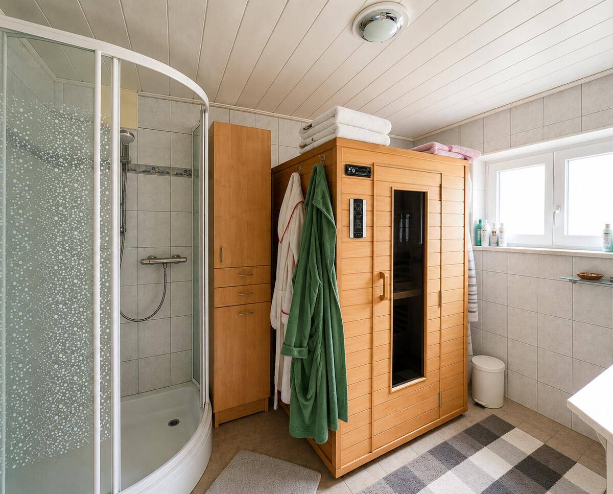 Badezimmer mit Duschkabine und integrierter Infrarotsauna für Wellnessmomente.