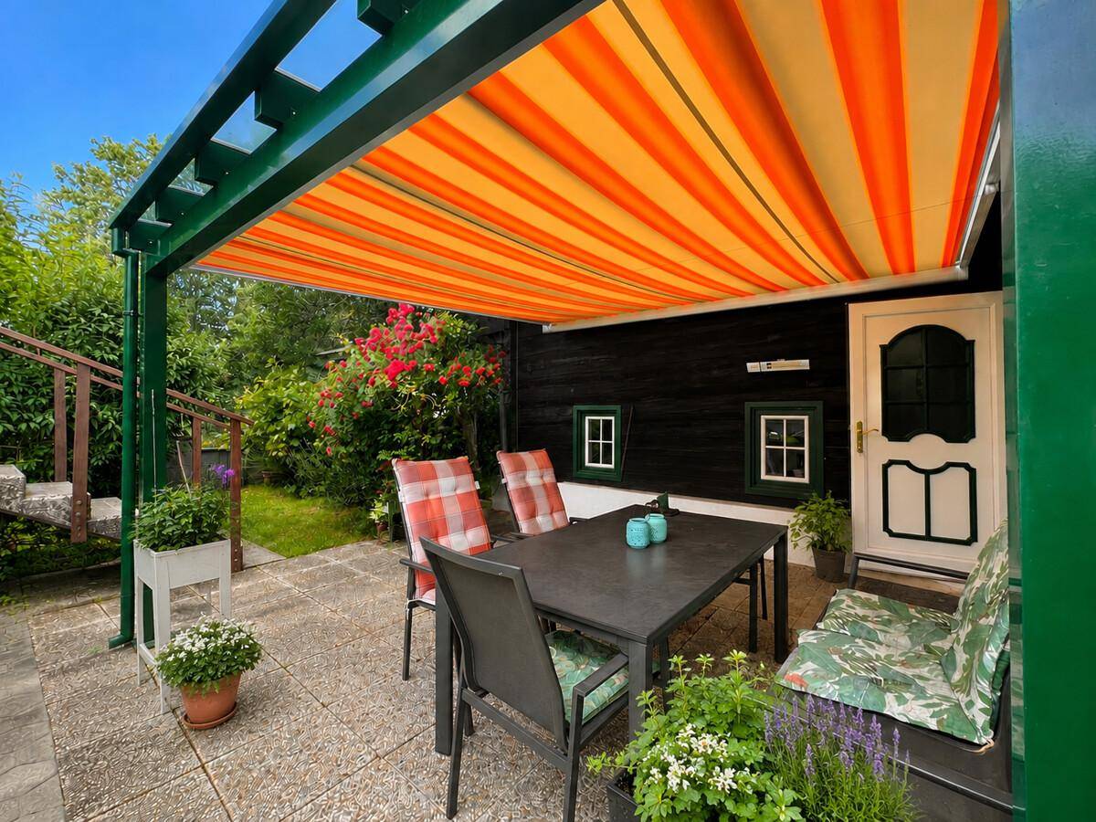Gemütliche Terrasse mit Markise, Gartenmöbeln und Blick auf den gepflegten Garten.