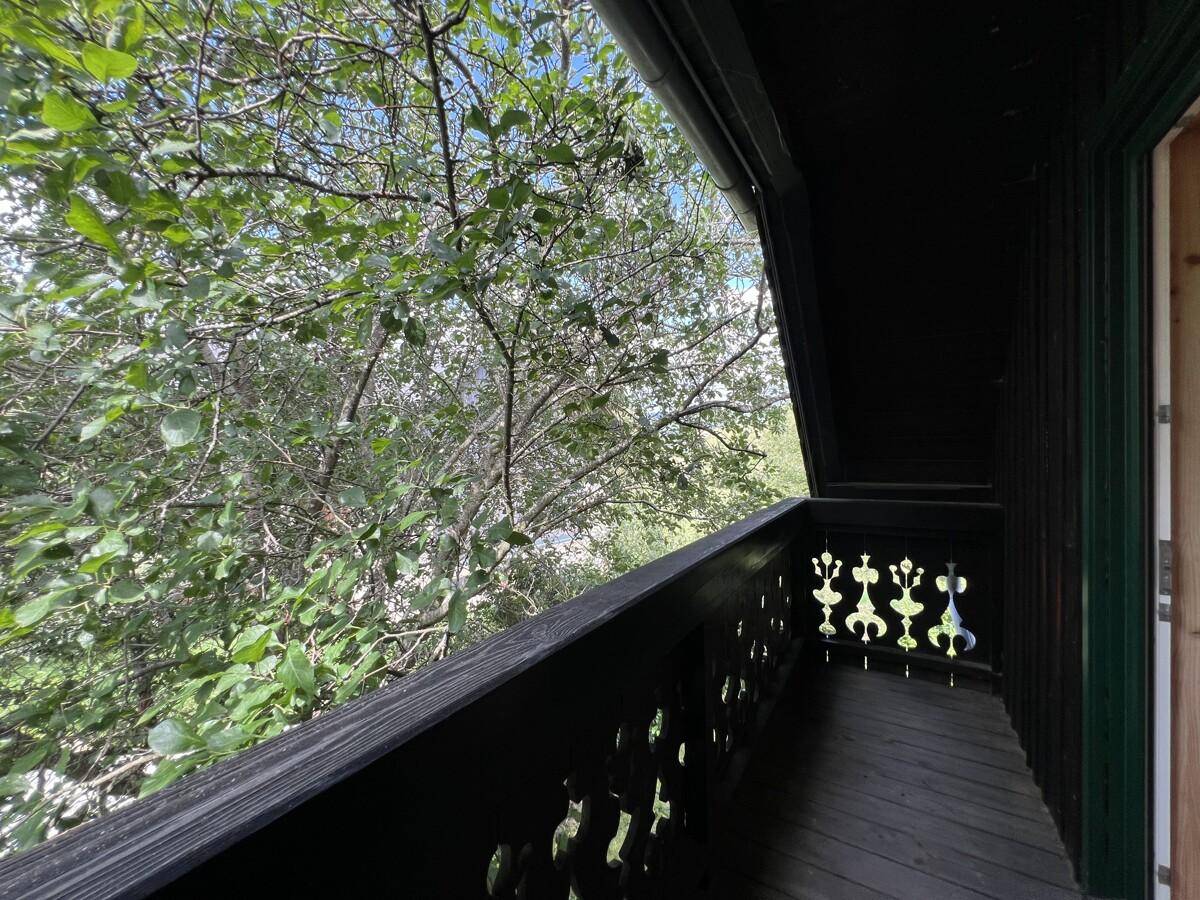 Schmaler Balkon mit traditionellem Holzgeländer und Blick ins Grüne.