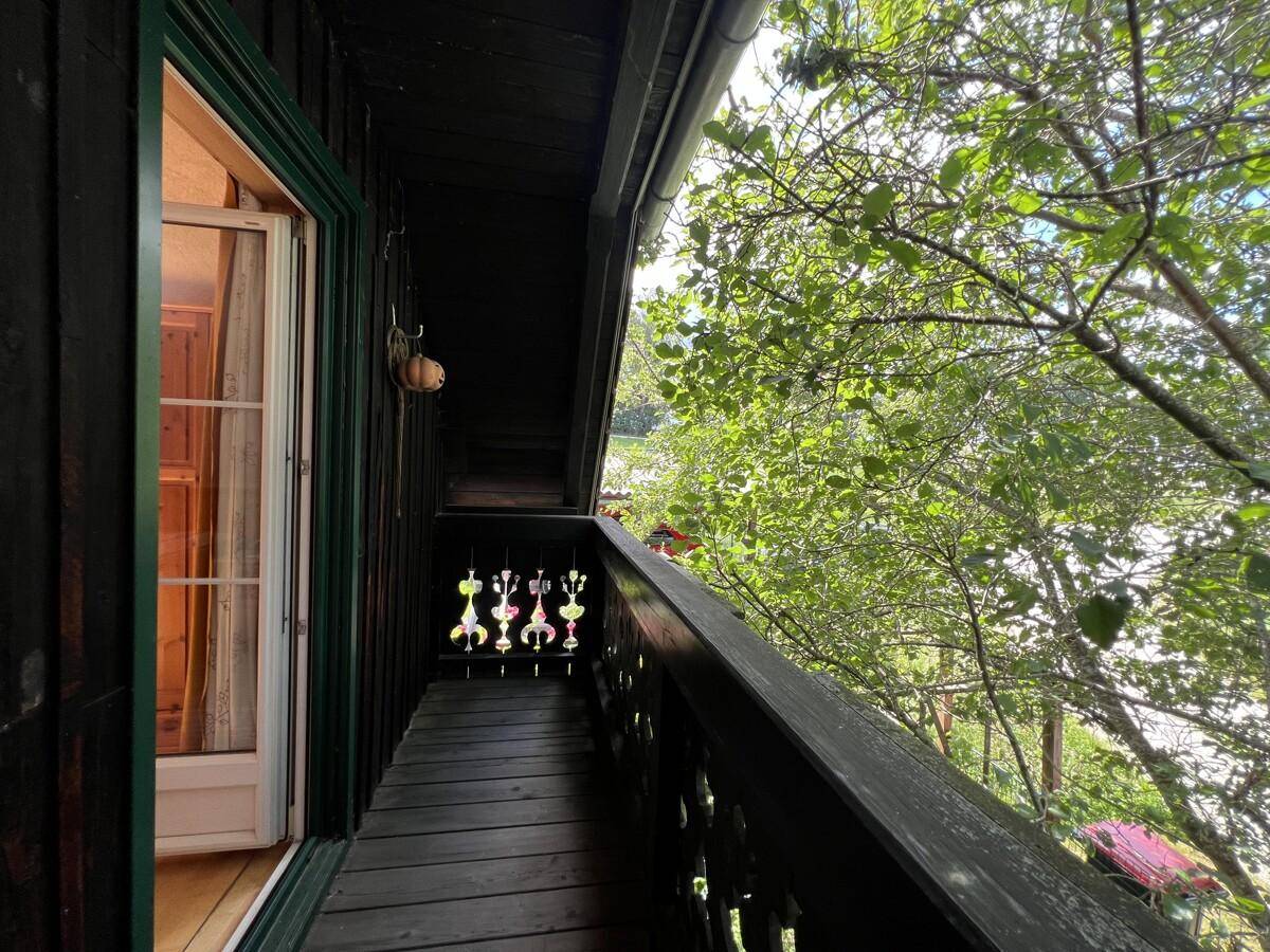 Kleiner Holzbalkon mit traditionellem Geländer und Blick ins Grüne.