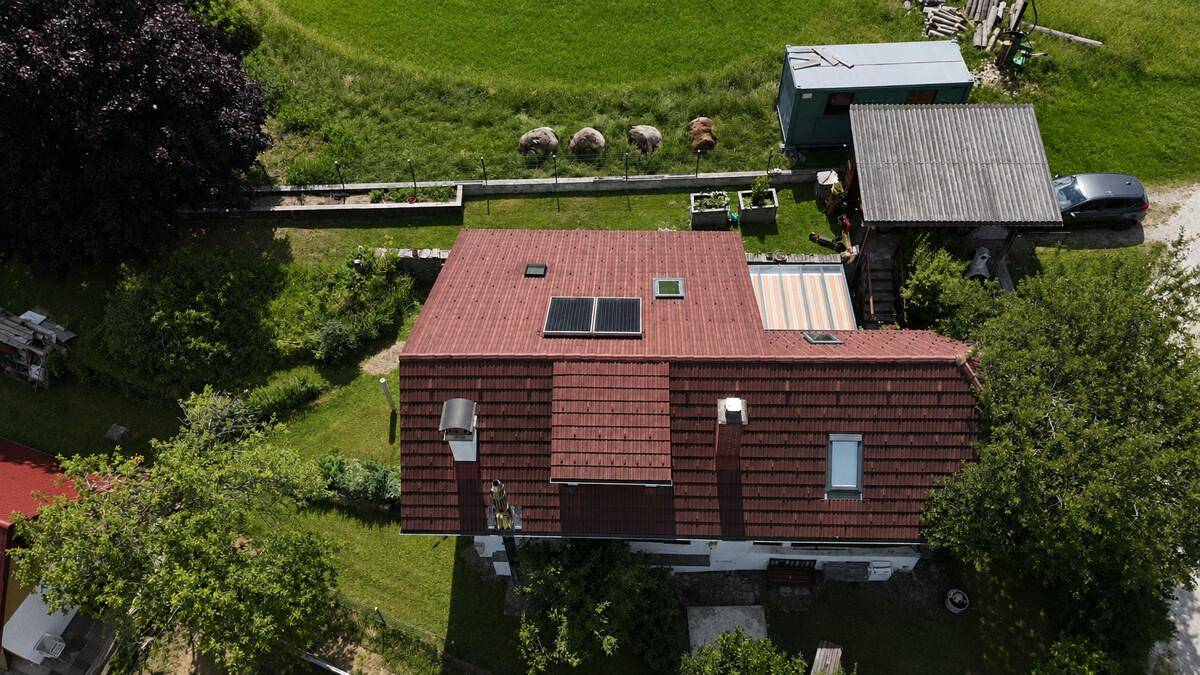 Luftaufnahme des Hauses mit rotem Ziegeldach, Solaranlage und umliegendem Garten.
