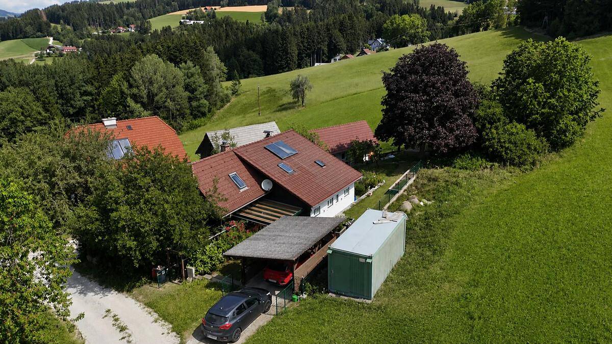 Luftaufnahme des Anwesens mit Carport, Nebengebäude und umgebender Natur.