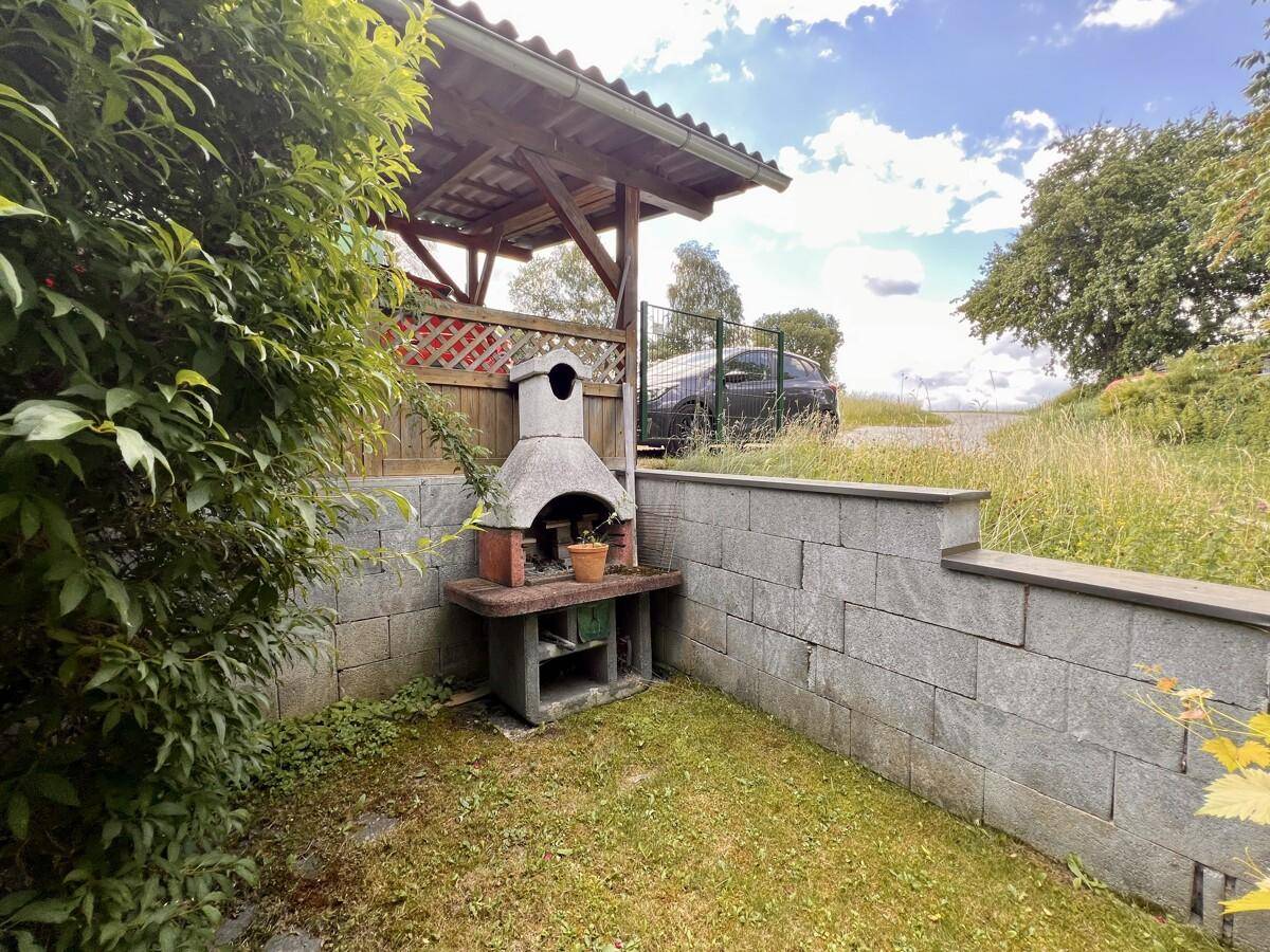 Gemütlicher Grillplatz im Garten mit gemauerter Feuerstelle und Sitzgelegenheit.