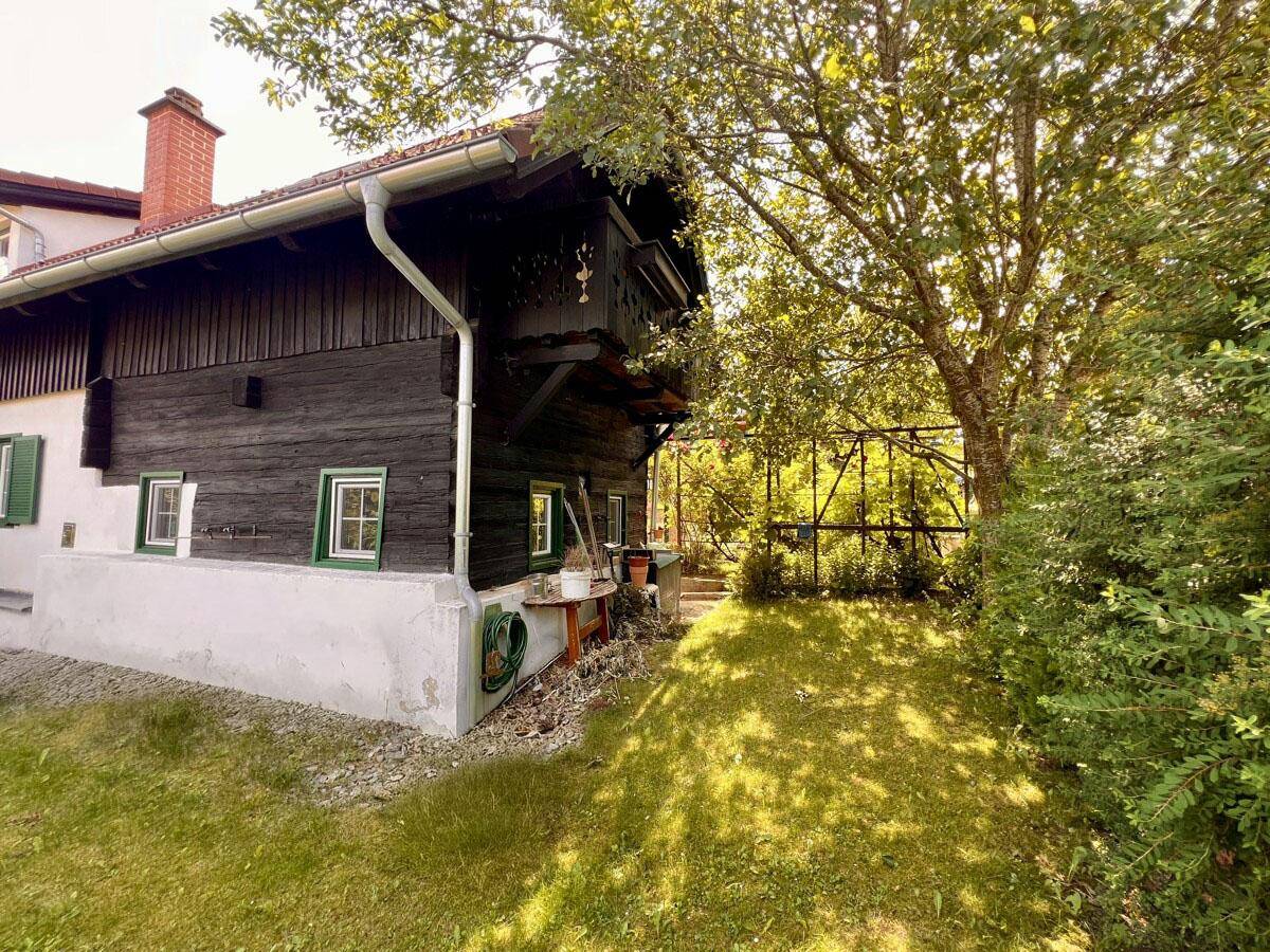 Traditionelles Holzhaus mit Balkon und umgebendem Gartenbereich.