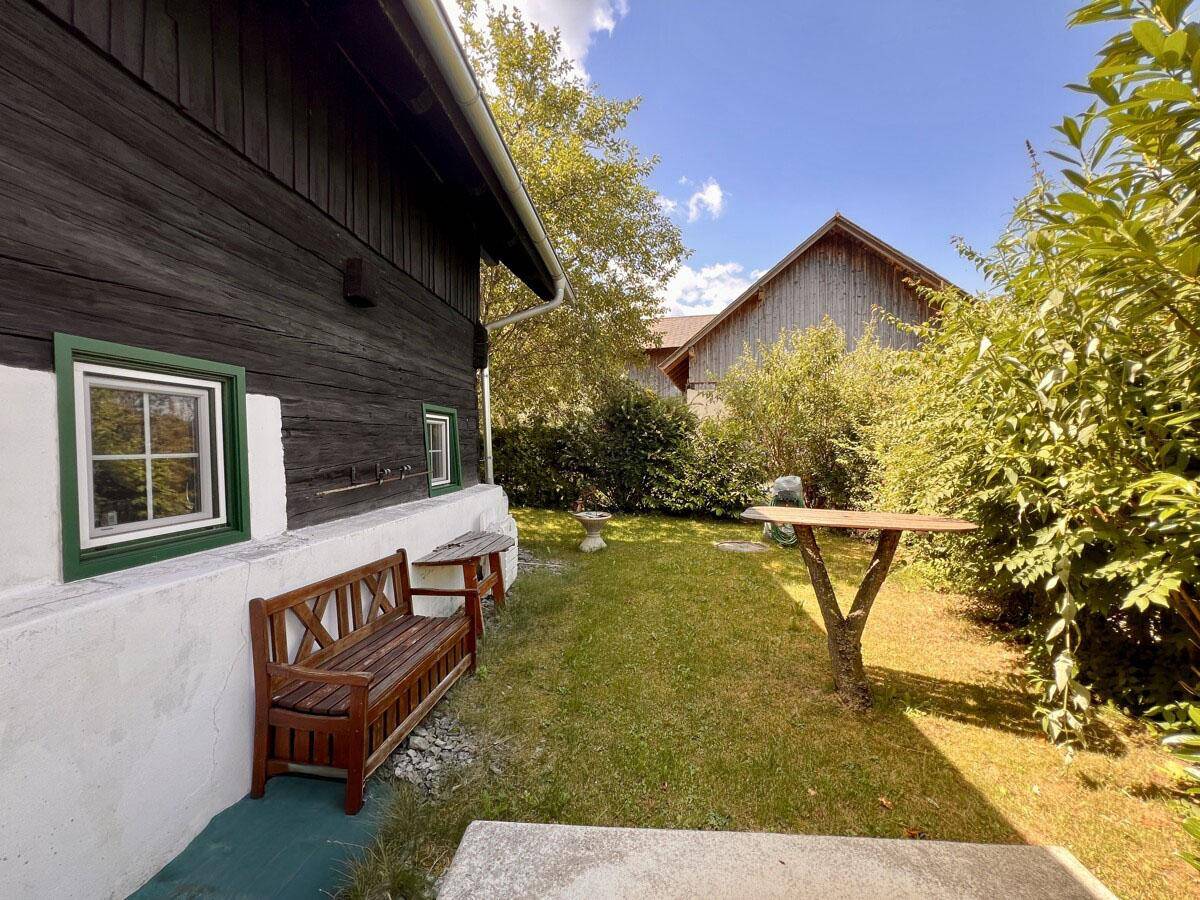 Kleiner Gartenbereich mit Holzbank und Blick auf das Nachbargebäude.