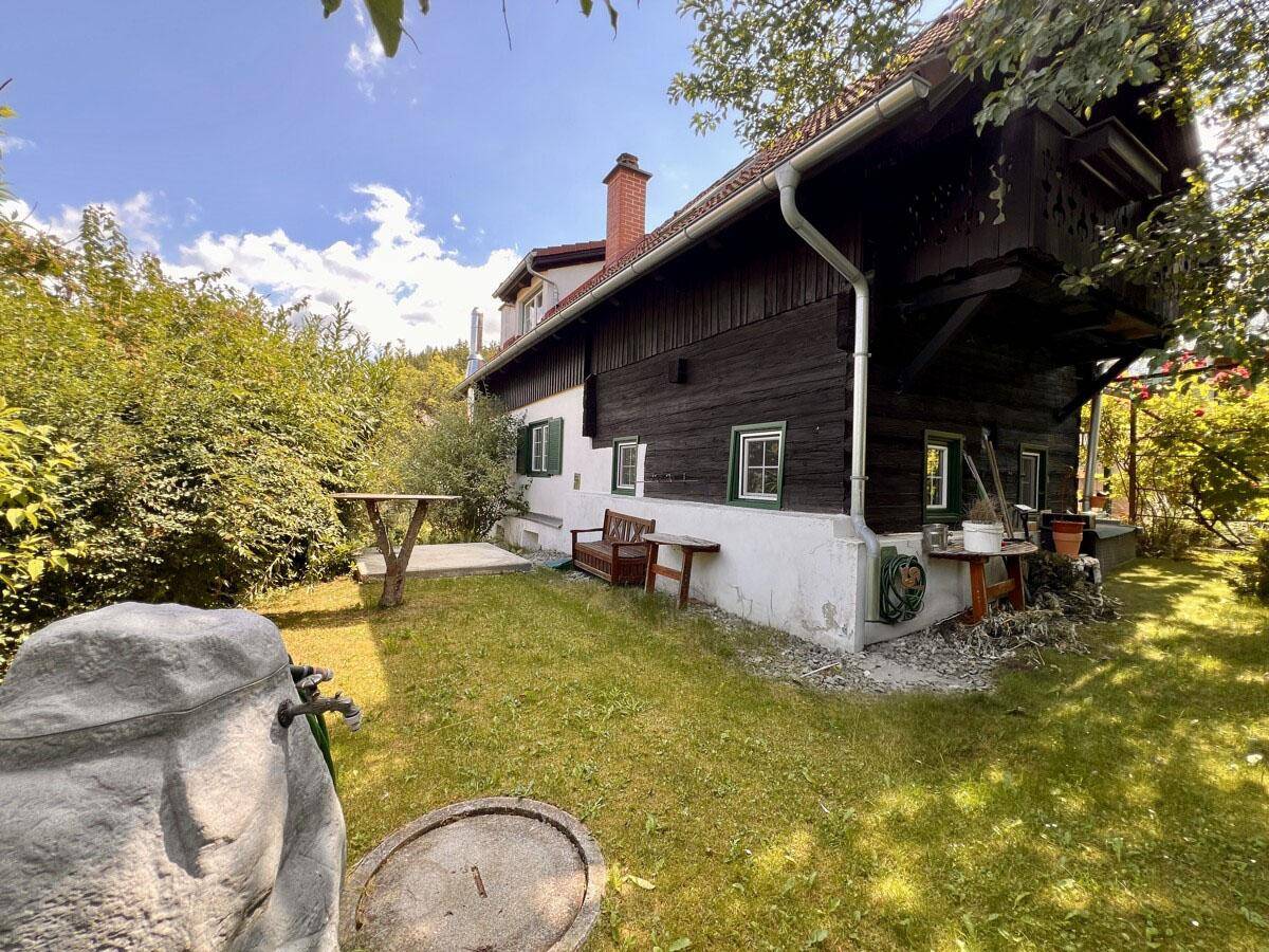 Traditionelles Holzhaus mit Kamin und gepflegtem Gartenbereich.