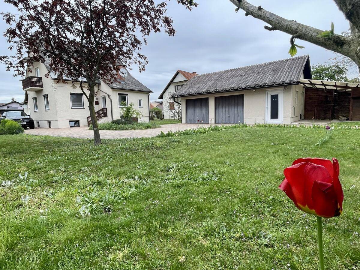 Weitläufiger Gartenbereich mit Rasenfläche, im Hintergrund das Haus und die Garage.
