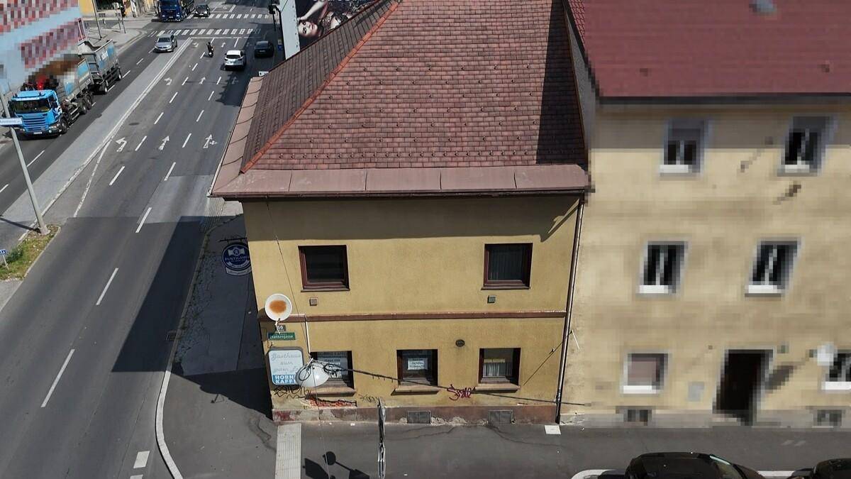 Nahaufnahme der Gebäudefassade aus der Luft, mit Blick auf die Straße und angrenzende Gebäude.