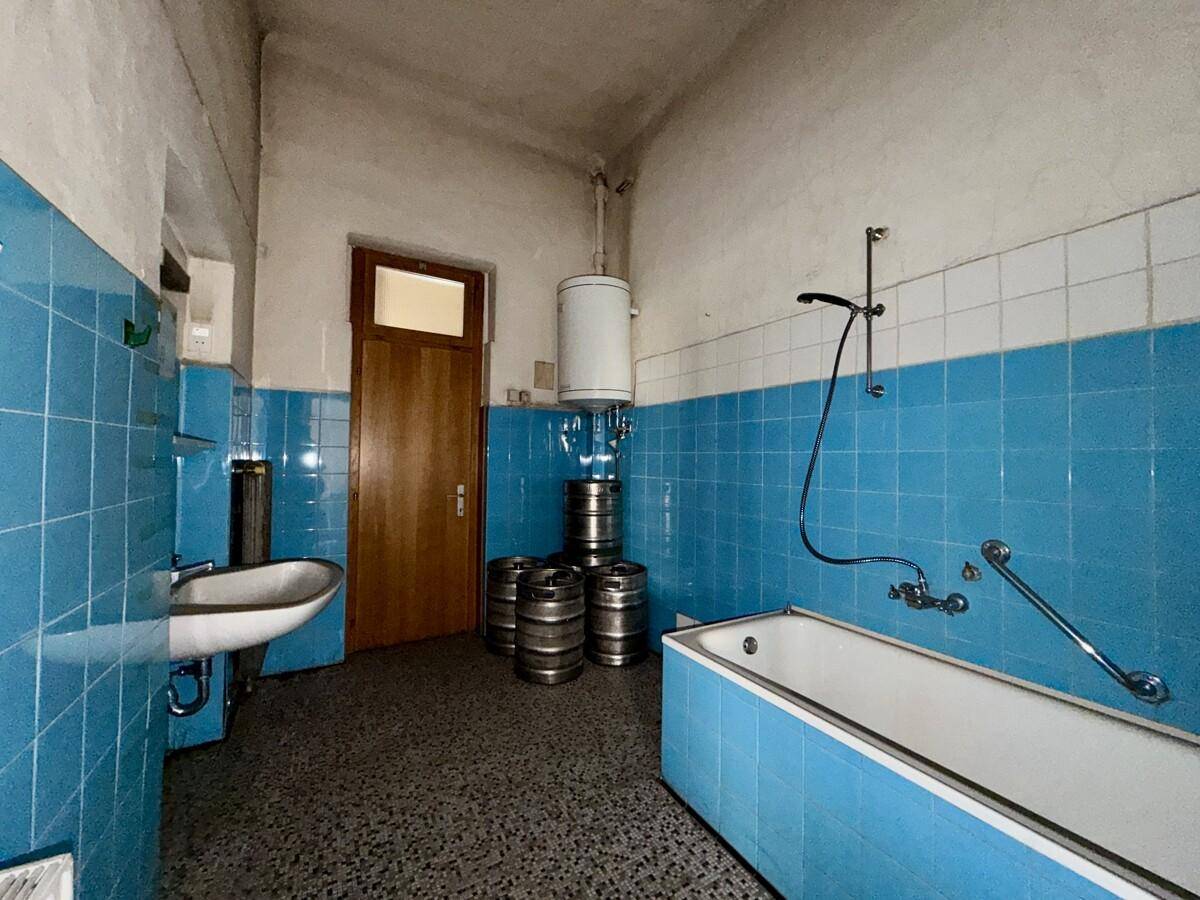 Badezimmer mit blauen und weißen Fliesen, einer Badewanne und einem Waschbecken.