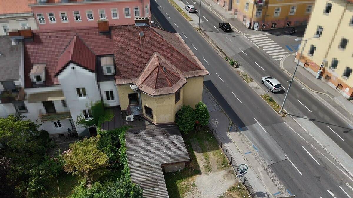 Luftaufnahme des Gebäudes und der umliegenden Stadtlandschaft mit Straßen und anderen Häusern.