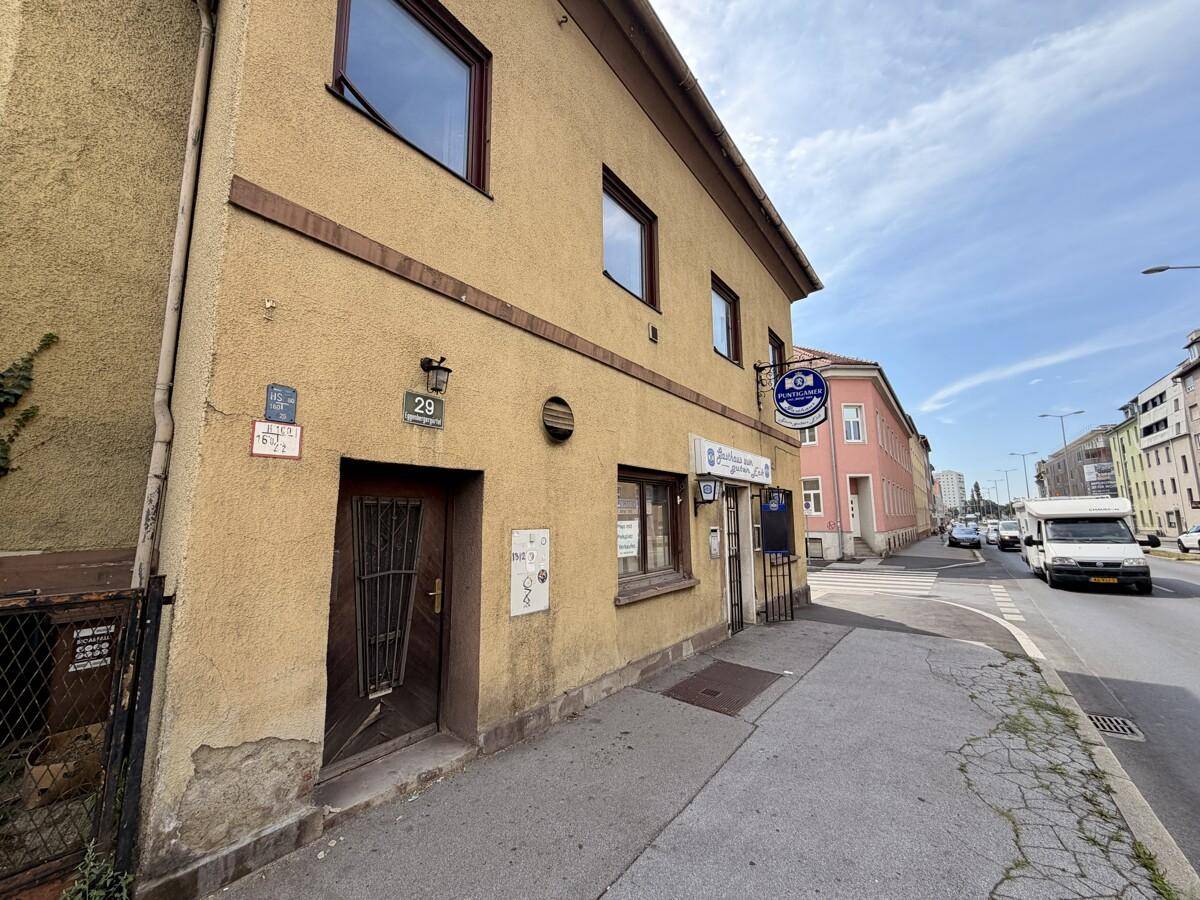 Fassade des Gebäudes im Erdgeschoss mit Eingangstür und Blick auf die belebte Straße.