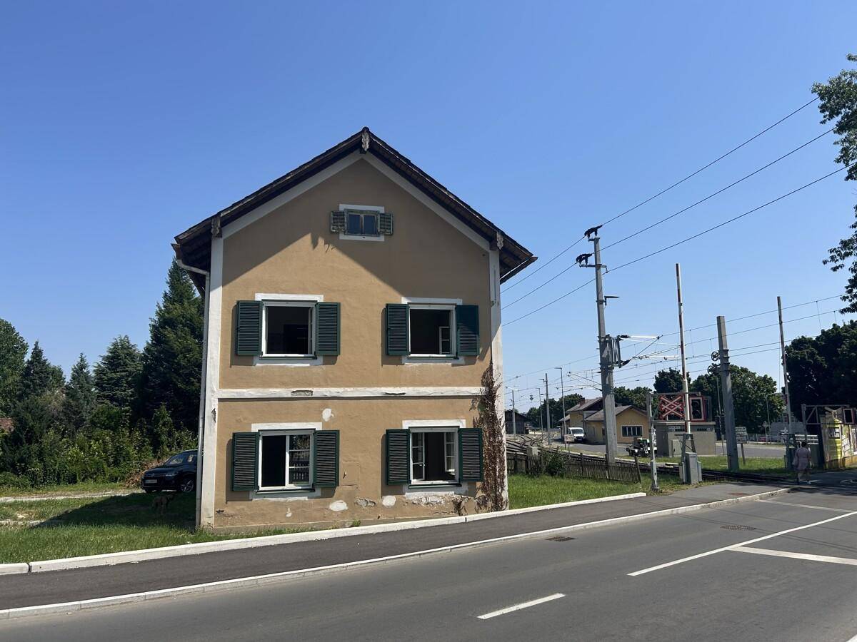 Fassade des historischen Hauses mit grünen Fensterläden und Blick auf die Straße und Bahngleise.