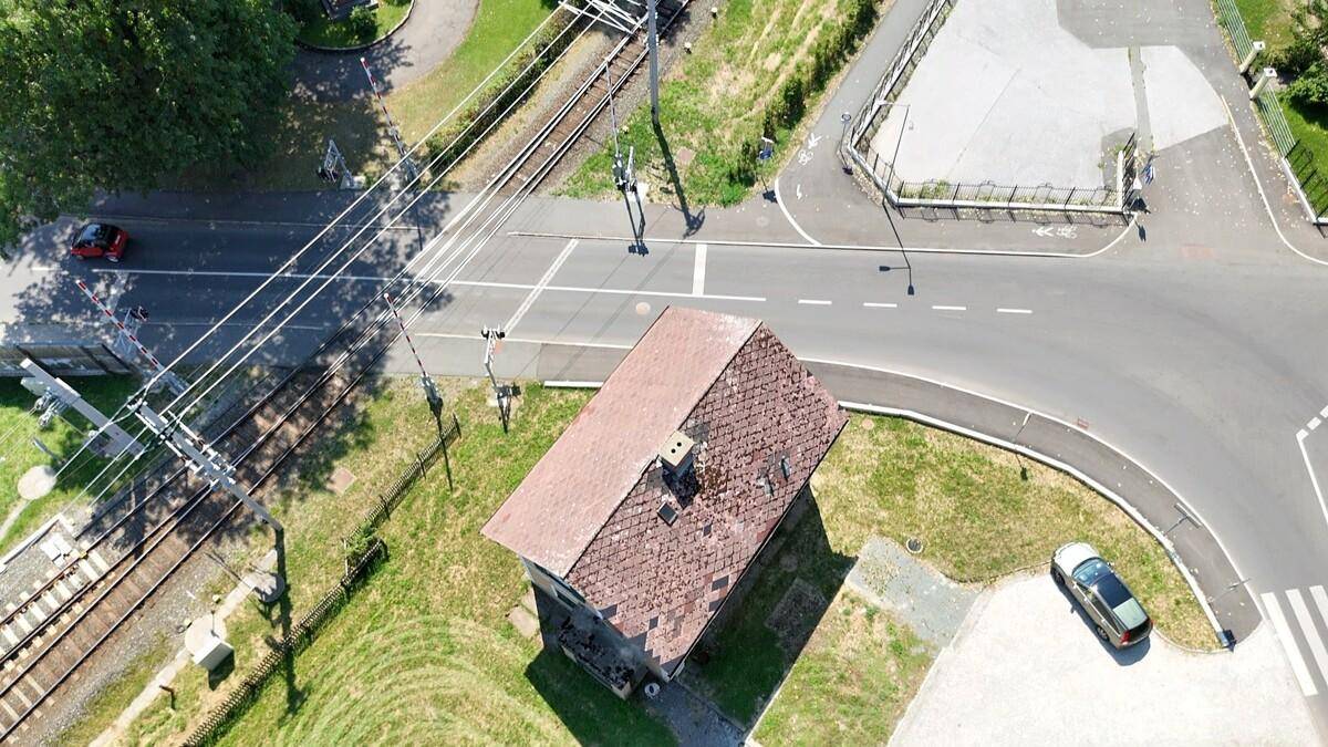Draufsicht auf das Haus mit Satteldach, angrenzenden Bahngleisen und einer Straße.