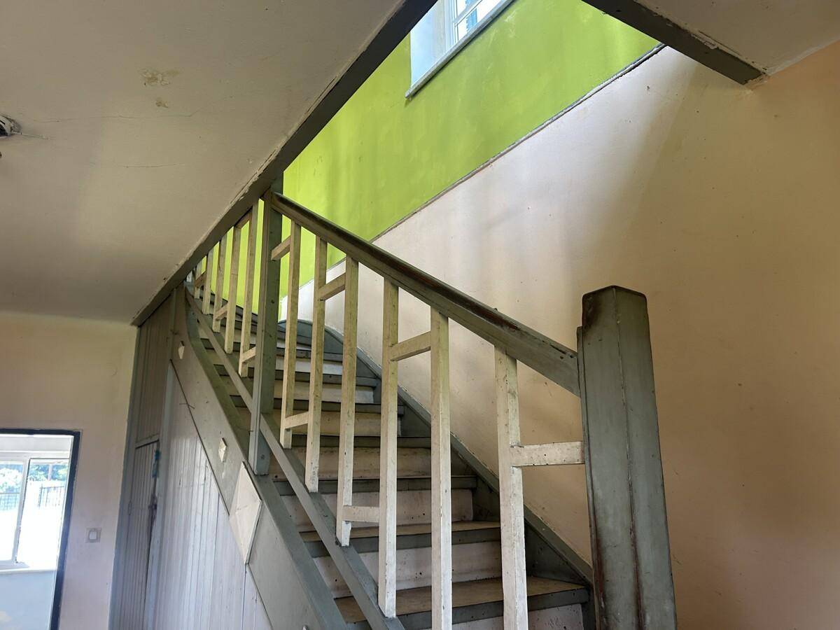 Holztreppe mit grün gestrichenen Wänden und einem Fenster, das Licht spendet.