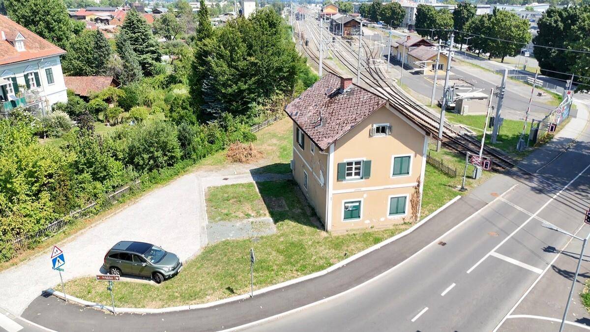 Vogelperspektive des Hauses an einer Kreuzung mit Bahngleisen und einer Straße.