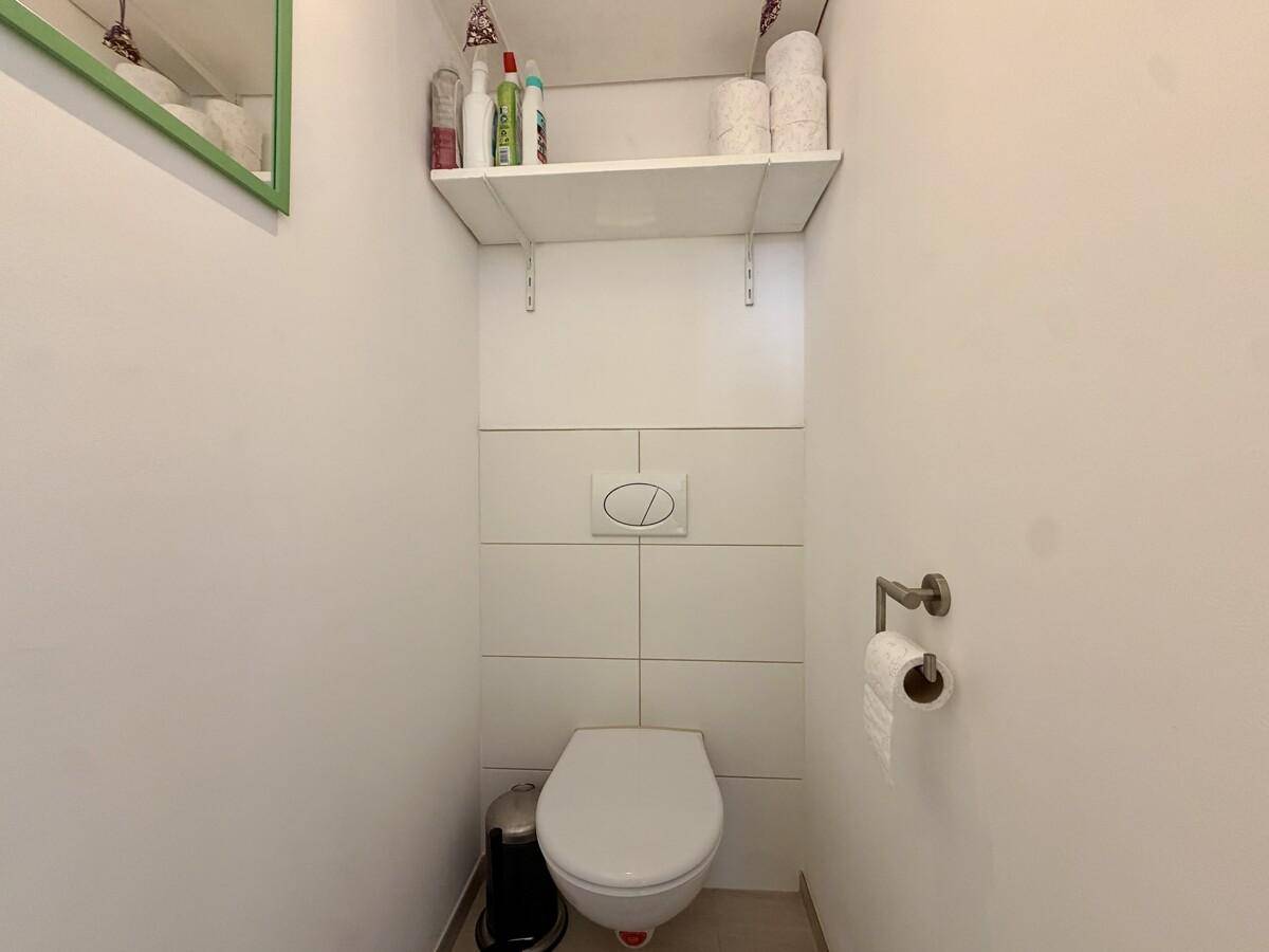 Kleines separates WC mit Wandtoilette und Fliesen an der Wand.