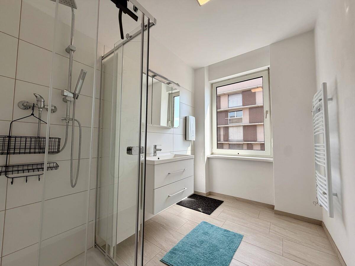 Modernes Badezimmer mit Duschkabine, Waschbecken und beheiztem Handtuchhalter.