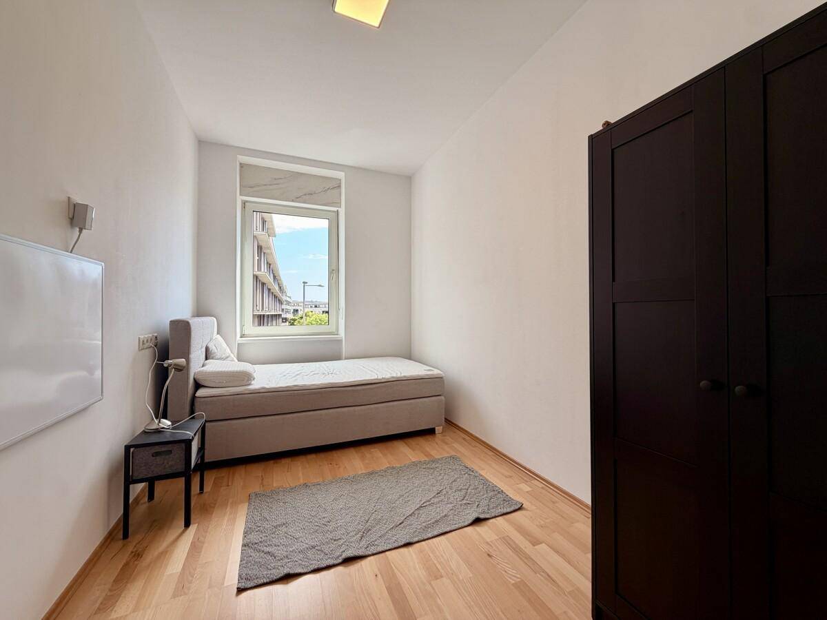 Gemütliches Schlafzimmer mit Einzelbett, Holzboden und einem Kleiderschrank.
