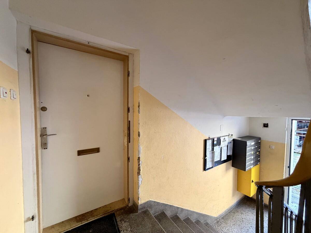 Treppenhaus mit Eingangstür und Briefkästen, das zu den Wohnungen führt.