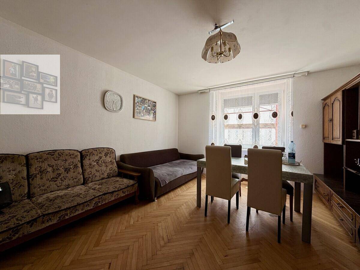 Gemütlicher Wohn-Essbereich mit Parkettboden, zwei Sofas und einem Esstisch am Fenster.