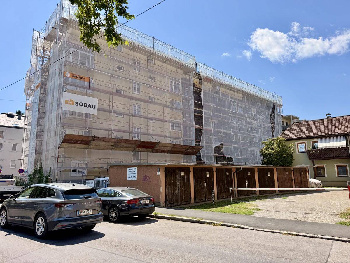 Mehrfamilienhaus unter Gerüst und Schutznetz, wahrscheinlich für Renovierungsarbeiten.