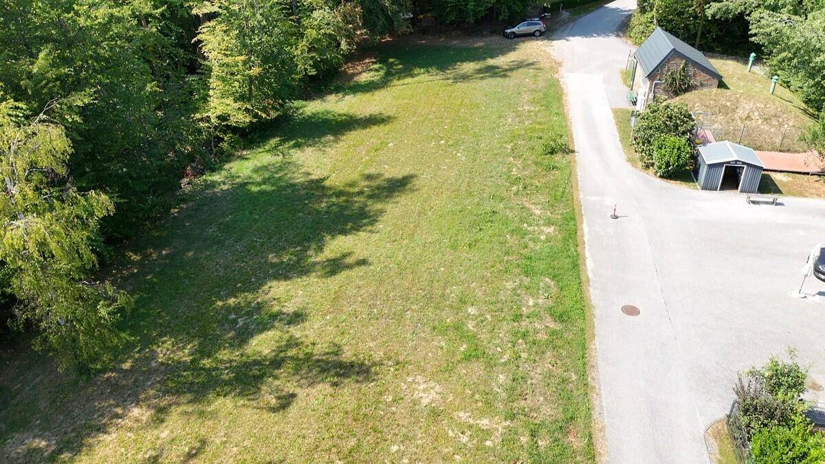 Luftaufnahme eines großen Grundstücks mit Wiese, Waldrand und angrenzender Straße.