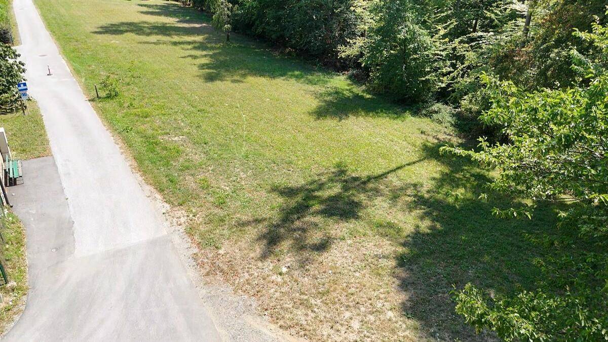 Luftaufnahme eines weitläufigen Grundstücks mit angrenzender Straße und Baumbestand.