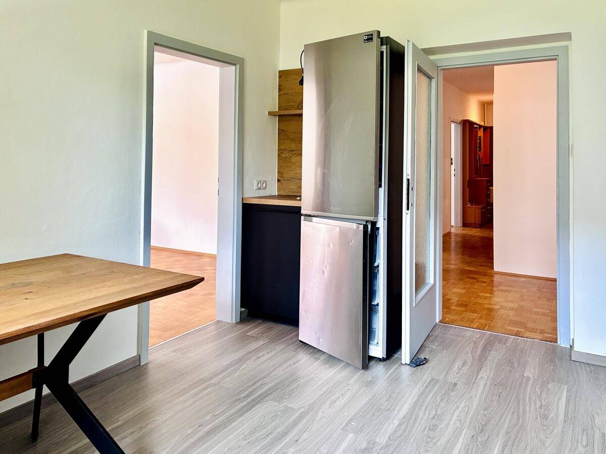 Essbereich mit Kühlschrank und zwei Türen, die zu anderen Räumen der Wohnung führen.