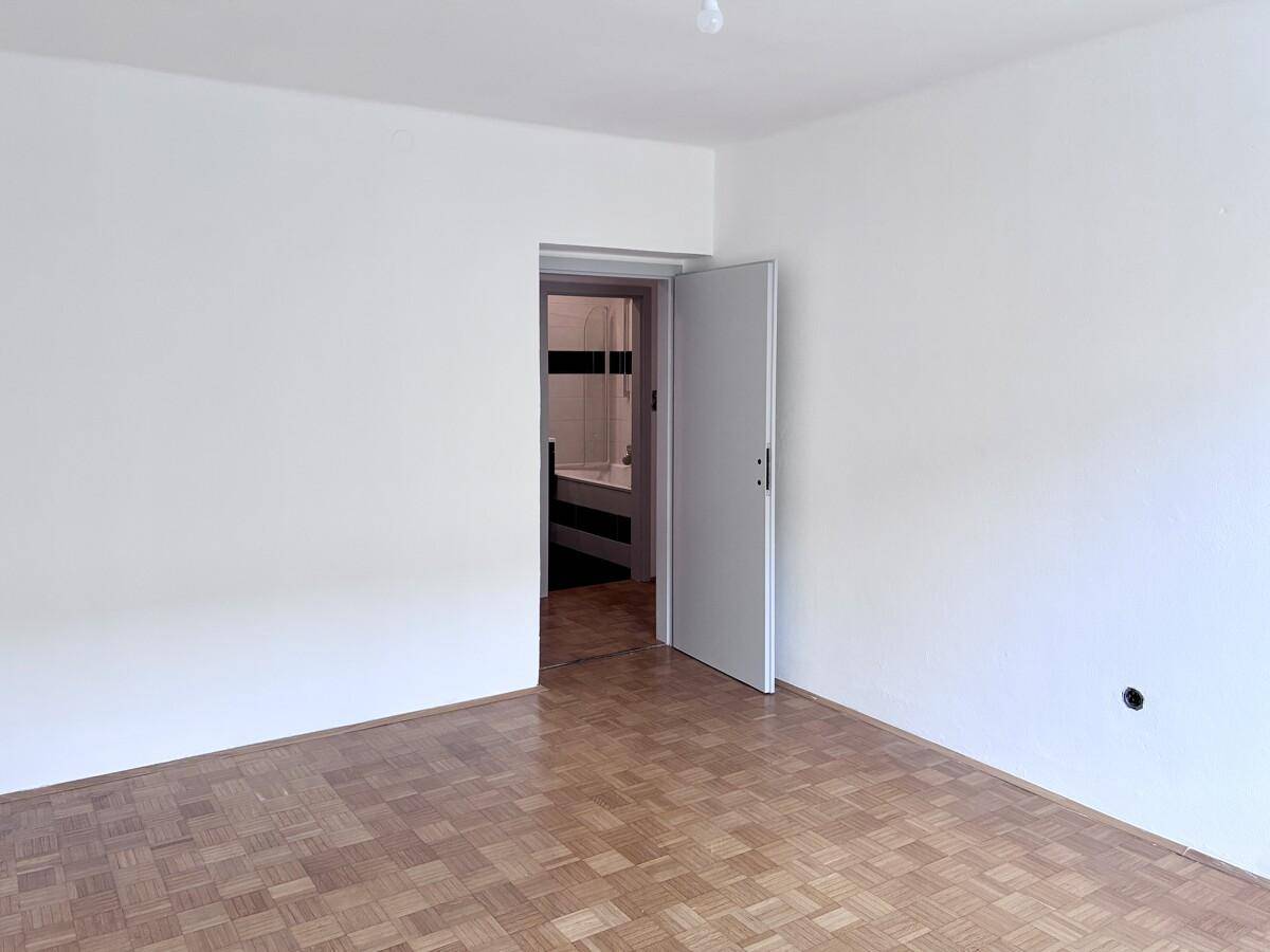 Helles Zimmer mit Parkettboden und direktem Zugang zu einem Badezimmer.